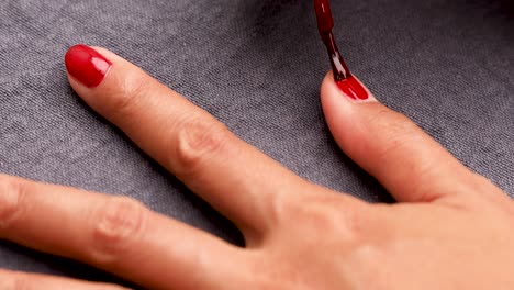 woman painting nails with red nail polish