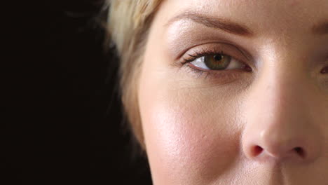 Closeup-of-a-female-eye-blinking-on-dark-studio