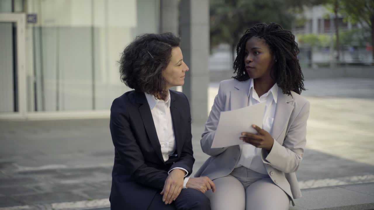 Donne d'affari serie sedute per strada a discutere un contratto.