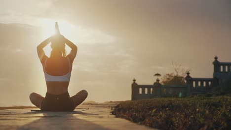 Silhouette-of-woman-doing-yoga-lotus-pose-prayer-with-magical-sunlight,-dusk