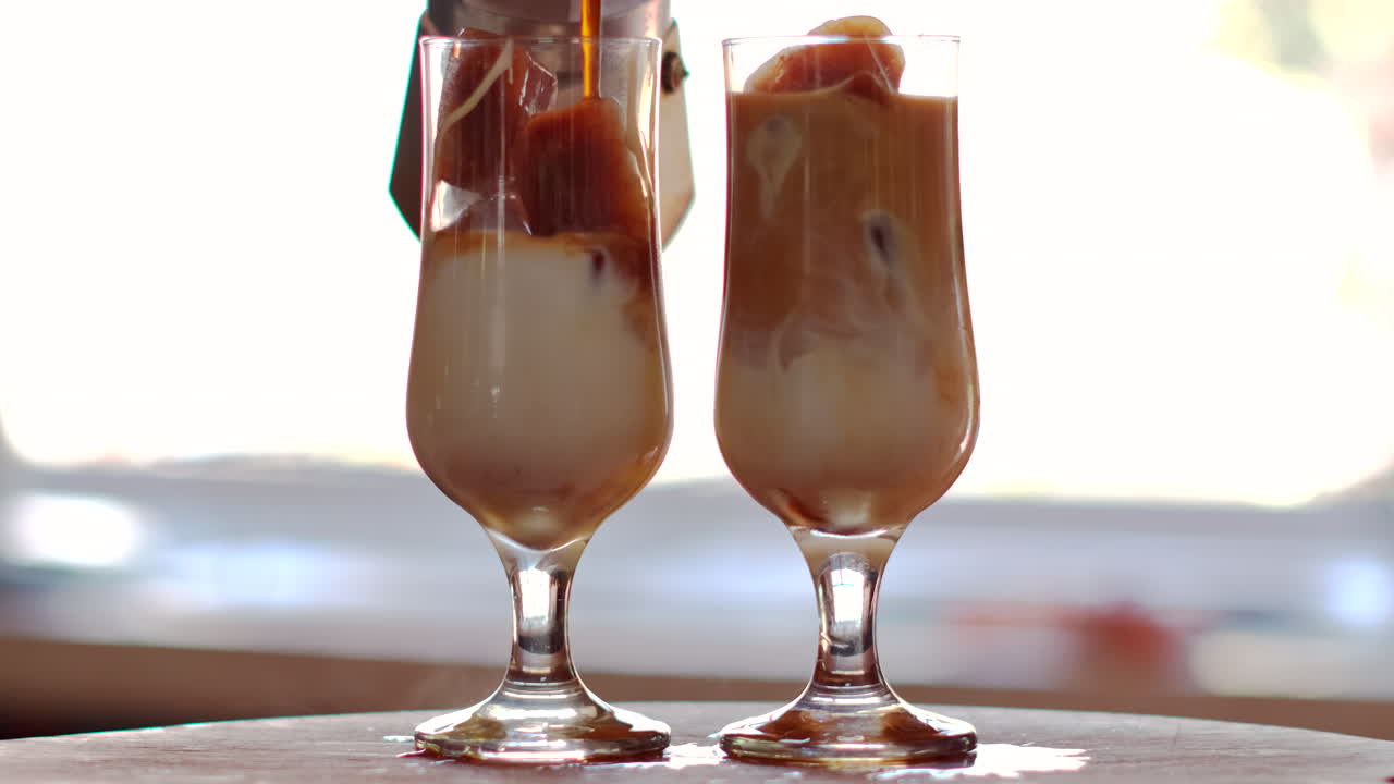 Caffè nero bollente versato dalla Moka in bicchieri con cubetti di ghiaccio al caffè