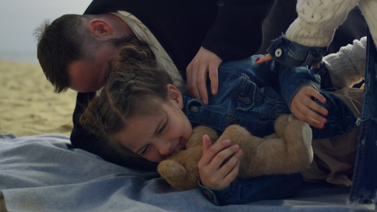 해변 모래에서 가족과 놀고 있는 웃는 소녀. 즐거운 아이 휴가를 즐기세요.