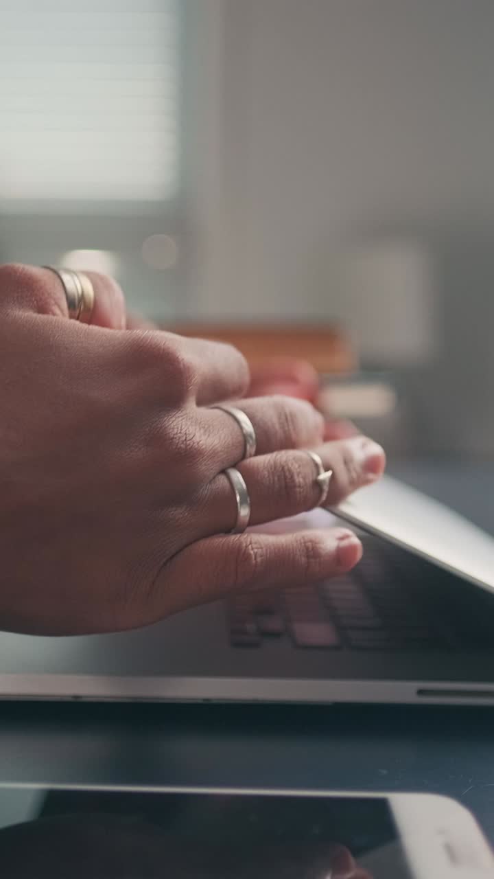 Hands typing on laptop in bright workspace with books nearby