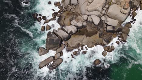 dark green sea washing and crashing waves on a big formation of rocks