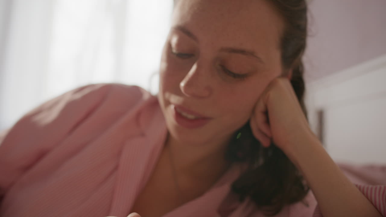 Young Mother Comforting Baby while Lying Together on Bed