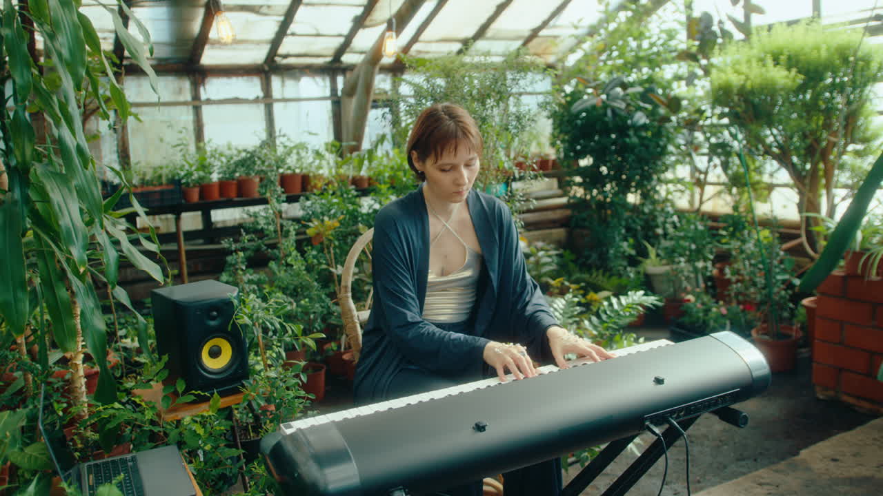 Female Pianist Playing Synth in Greenhouse with Lush Plants and String Lights