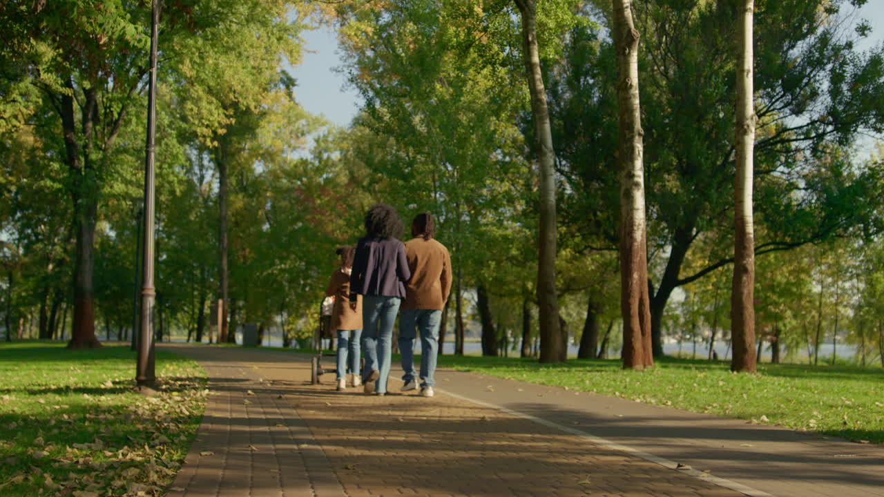 padres casuales caminando en el parque de otoño vista trasera. concepto de fin de semana feliz en familia.