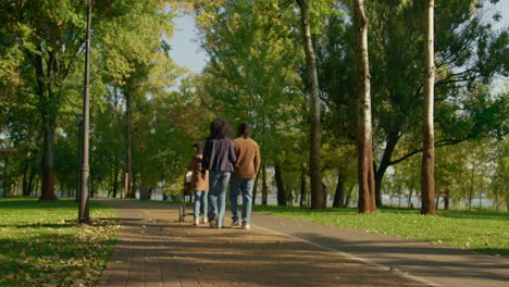 casual parents walking autumn park rear view. happy family weekend concept.