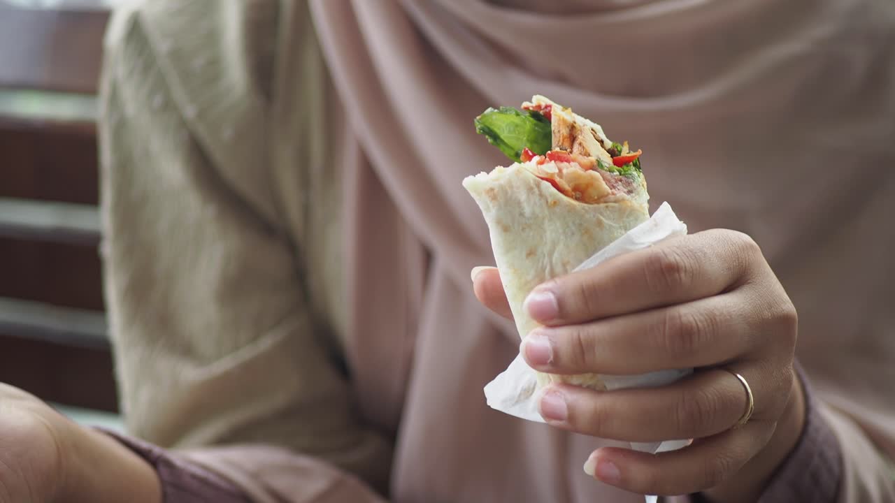 Woman in Hijab Enjoying a Delicious Shawarma Wrap