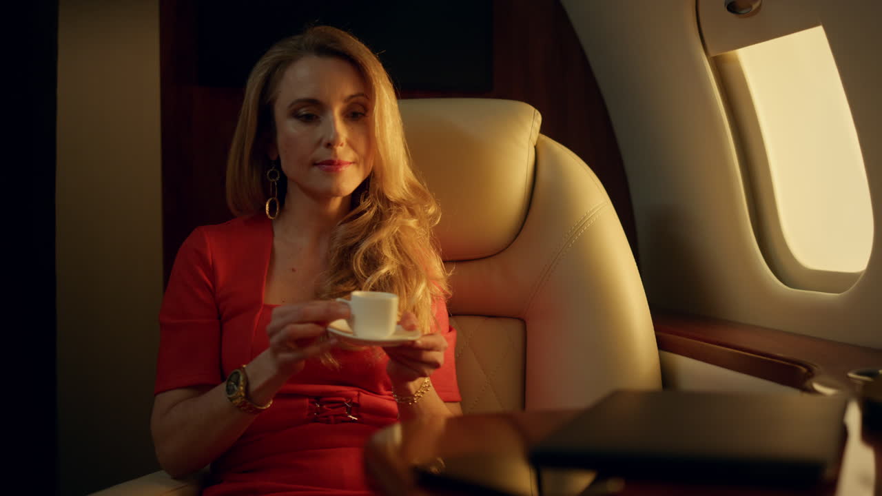 Imprenditrice stanca che si riposa in aereo, primo piano. Bella bionda che beve caffè.