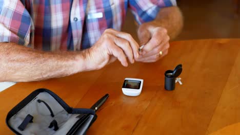 senior man checking blood sugar on glucometer 4k