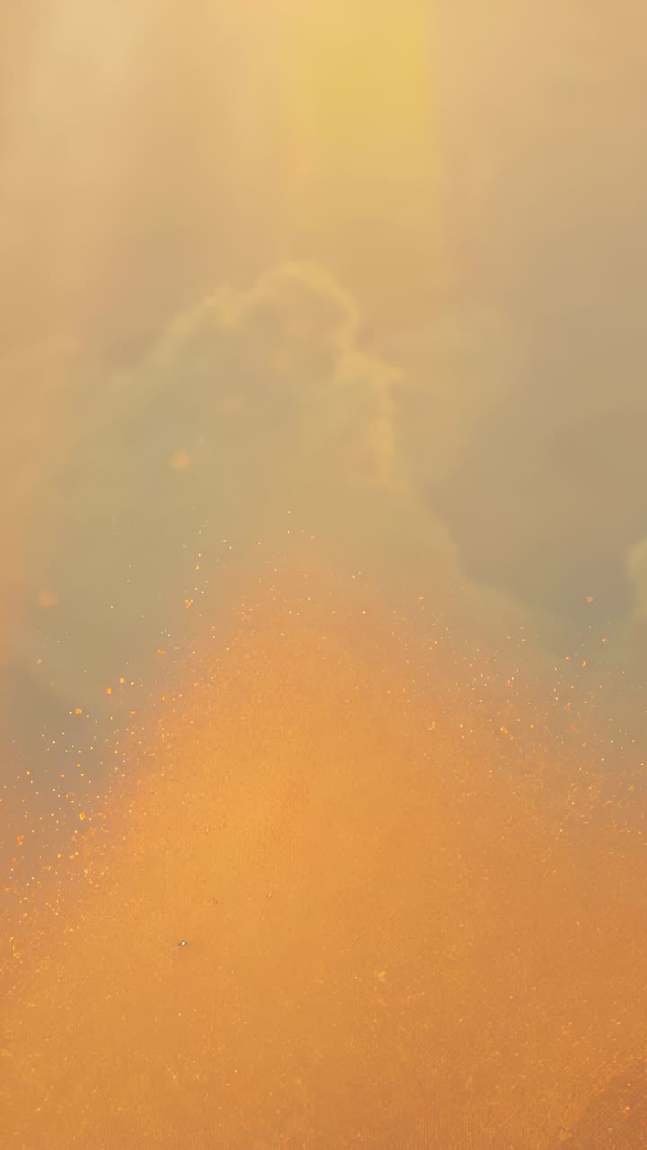 Vertical video: Falling yellow beams driving golden pile softening, sparkles shifting in closeup