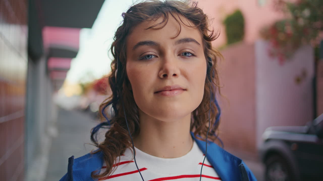 feliz melómano de pie en la calle con auriculares de cerca. retrato de una mujer escuchando