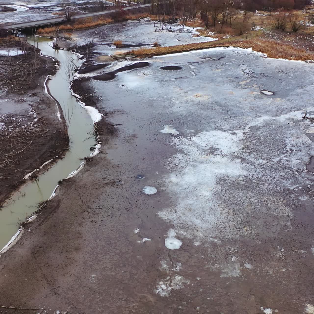 Nature in danger. Gloomy background of a river and fields in spring. Environmental problems. Aerial flight