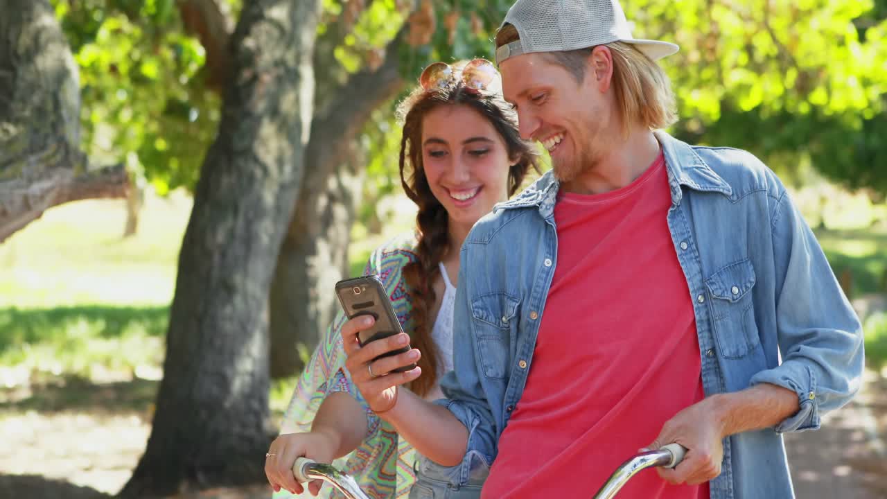 Couple using phone while riding bicycle 4k