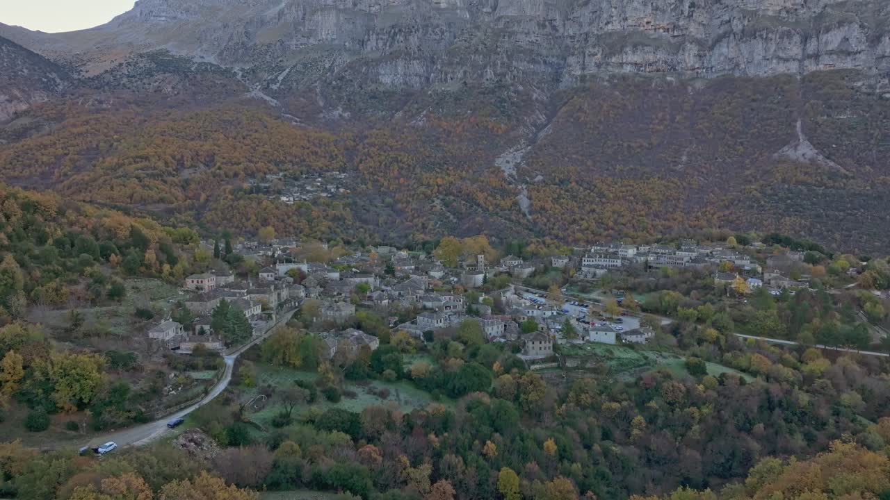 Droneoptagelse af en stenlandsby, der gløder ved solopgang i en efterårsskov, Papigo