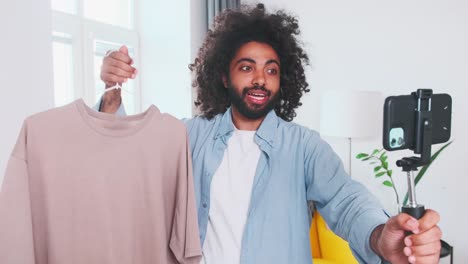 joven árabe escribe un blog de moda con camiseta y teléfono móvil