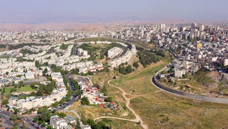 aerial view of a middle eastern city divided by a security barrier