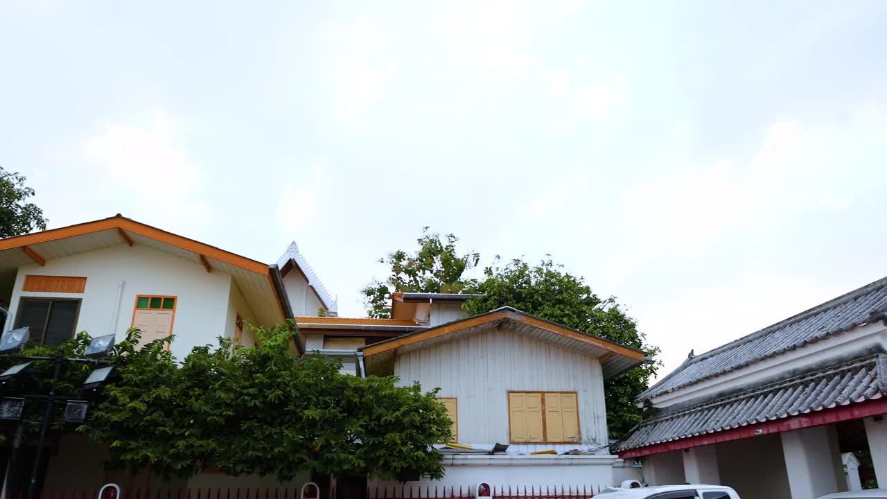 A serene 10-second video capturing a traditional Thai house surrounded by lush greenery in Bangkok, with gentle camera panning