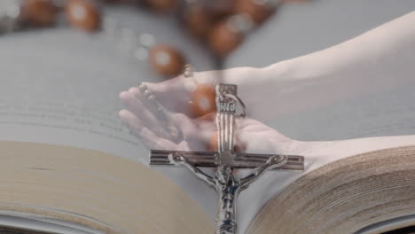 animation of caucasian woman praying with rosary over cross and bible