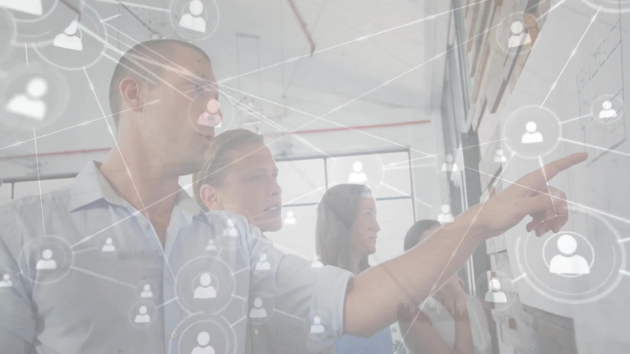 Business team pointing at wall while network icons fading in and illustrating collaboration