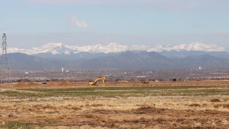 Equipo-De-Construcción-Trabajando-En-Un-Desarrollo-De-Vivienda-Cerca-De-Denver,-Colorado-Con-La-Cordillera-Frontal-De-Las-Montañas-Rocosas-En-El-Fondo