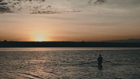 Sportliche-Männliche-Silhouette-Rudert-Und-Entspannt-Auf-Dem-Farbenfrohen-See-Bei-Sonnenuntergang