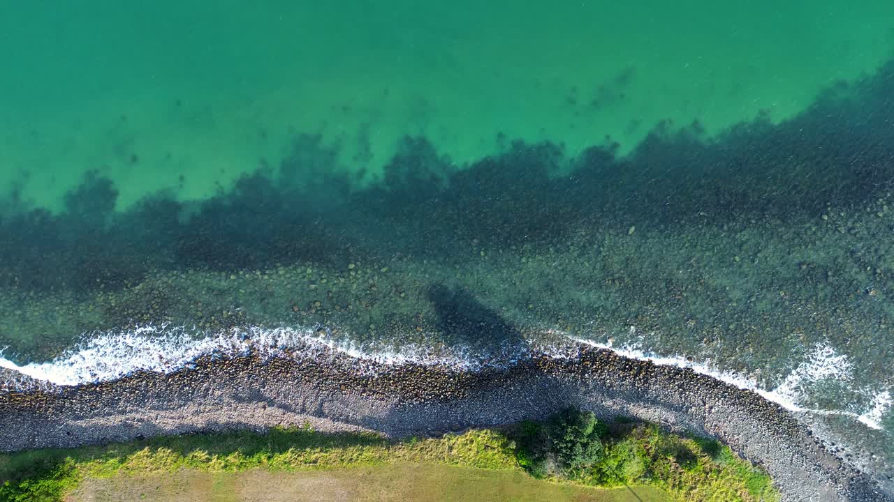 Drone aerial landscape of ocean waves breaking along rocky harbour reef embankment in crystal clear water inlet channel bay cove at Crowdy Head Mid North Coast Taree Australia travel tourism holidays