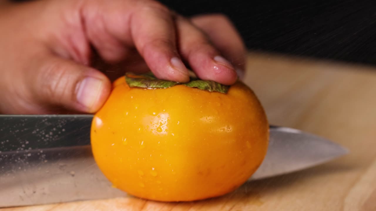 un caqui siendo cortado en una tabla de cortar