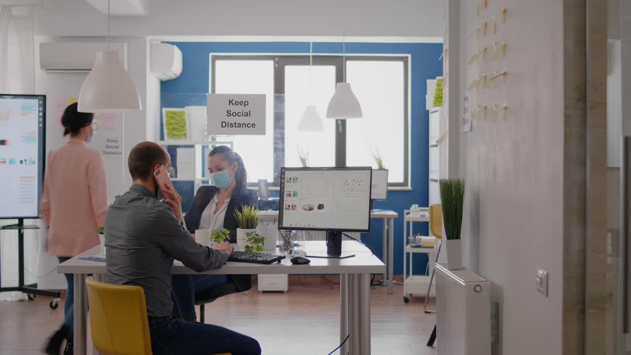 보호 얼굴 마스크 를 착용 한 사업가 가 전화 로 이야기 하고 있다