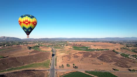 flying by a hot air balloon floating over the temecula vineyards in southern california, aerial