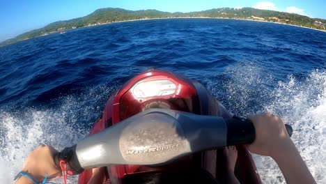 colpo pov di cavalcare una moto d'acqua verso un'isola caraibica in honduras