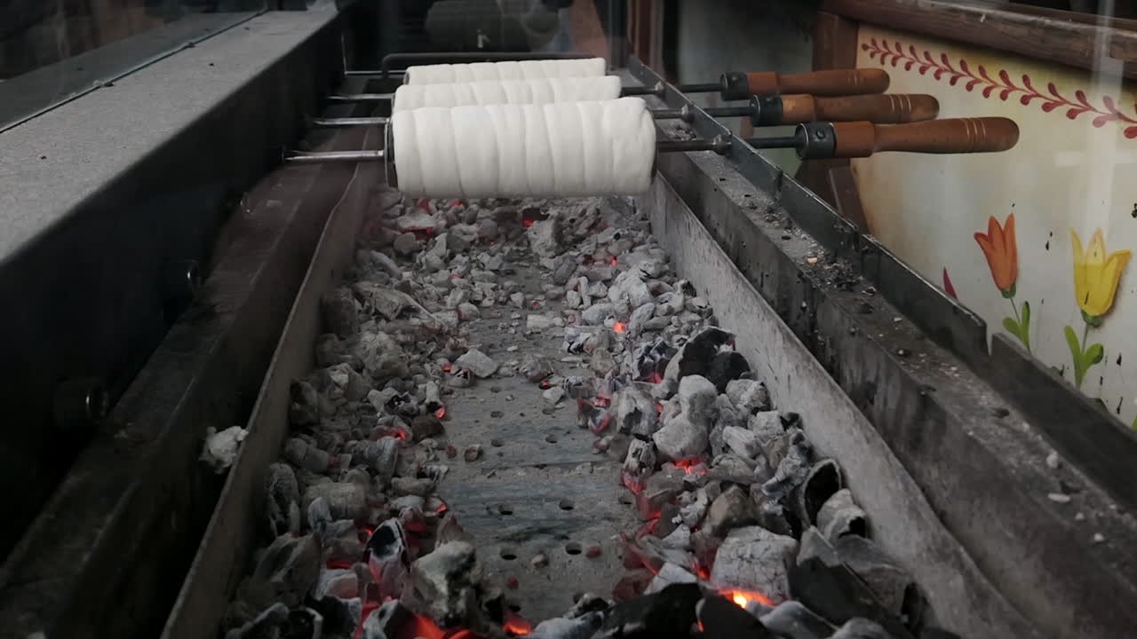 Hungarian specialty Chimney Cakes rotate on charcoal spit outdoors