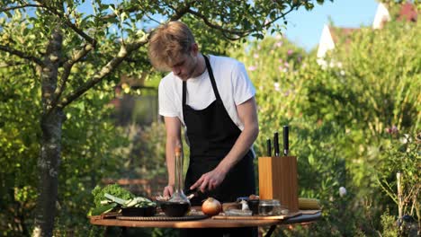 young man preparing things for grilling on a wooden table in his garden