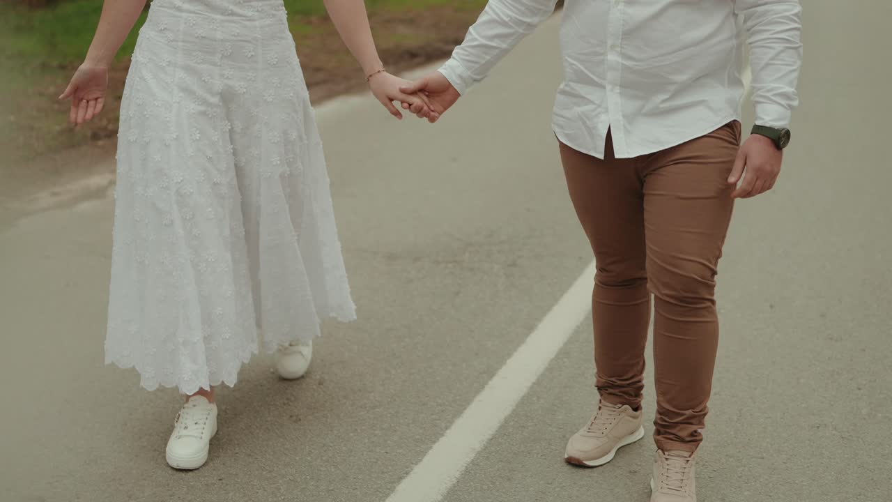 一对男女手牵手，一同走在铺砌的道路上