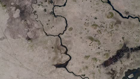 Mirando-Directamente-Hacia-Abajo-Desde-Un-Dron-A-Las-Marismas-Vacías-Del-Desierto-En-Islandia-Con-Pequeños-Arroyos-Goteando