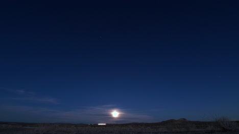 the moon rising from the horizon and illuminating the land - time lapse