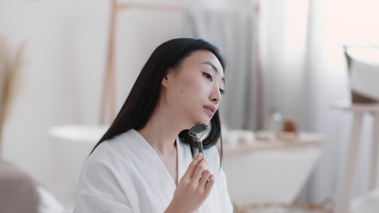 얼굴 마사지를 위해 재드 롤러를 사용하는 여성