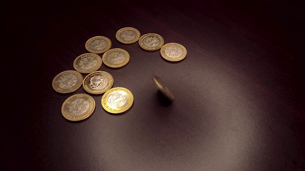 moneda de 10 pesos girando a mano sobre una mesa de madera