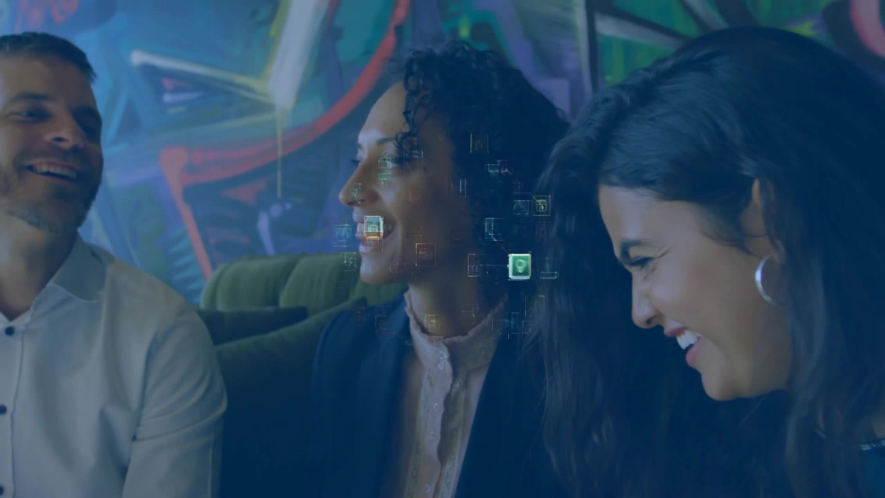 Donna al centro che parla, un collega a destra osserva le icone dell'interfaccia utente tecnologica che si espandono sul suo viso, mentre il gruppo ride.