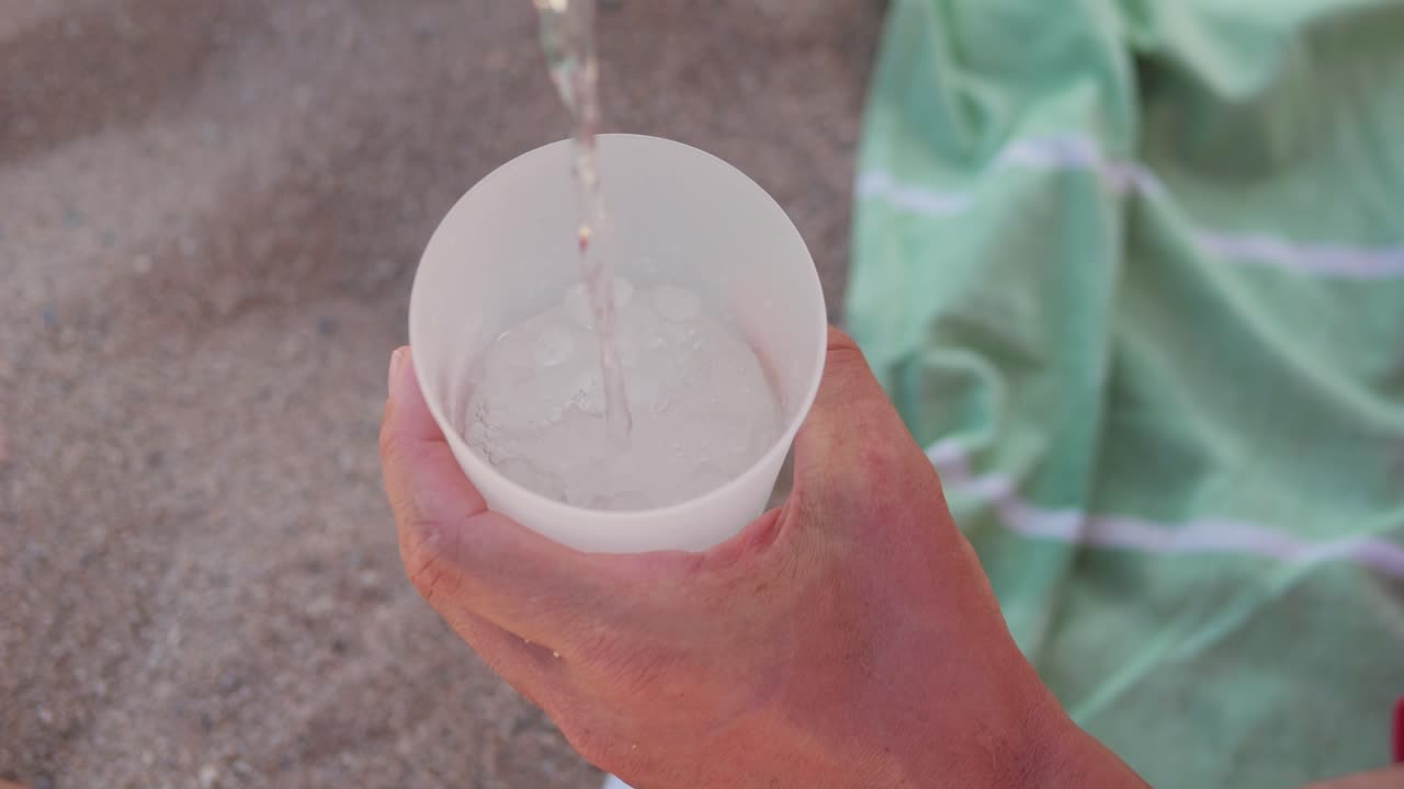 Pouring water into a cup on the beach