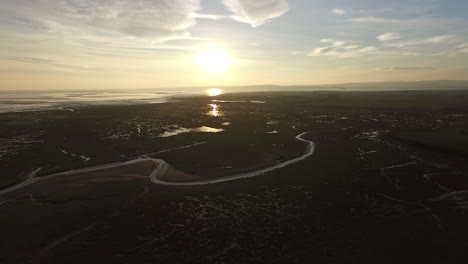 A-shot-of-the-sun-setting-over-the-coastal-line-of-the-English-Lake-District,-shot-from-above-moving-forwards