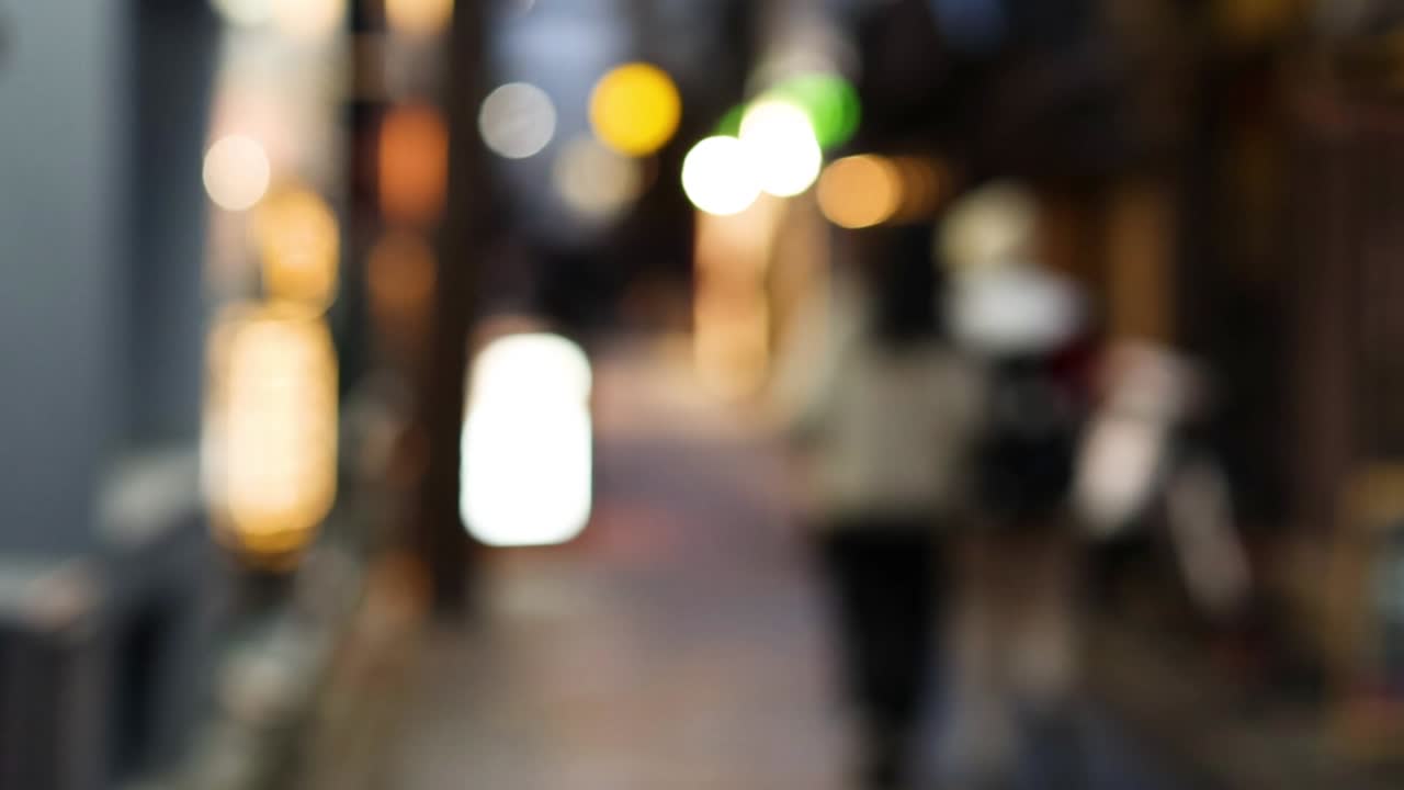 조명 된 골목길 을 고 있는 초점 이 벗어난 인물 들