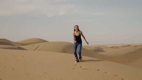 imágenes en cámara lenta de una mujer alegre con cabello largo corriendo por las dunas de arena en el desierto de gobi