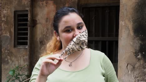 Happy-Indian-girl-standing-outdoor-while-taking-off-her-protective-face-mask-and-looking-at-camera-after-immunization-from-Covid19