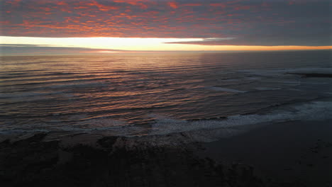 Establishing-Aerial-Drone-Shot-Over-Sea-at-Stunning-Sunrise-Panning-Down-in-North-Yorkshire-at-Low-Tide-UK