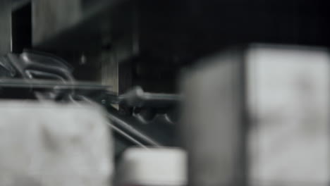 primer plano de una gran máquina de moldeo de piezas metálicas hidráulicas que toma un producto y lo presiona en forma en cámara lenta
