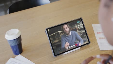 caucasian businesswoman on tablet video call with caucasian female colleague on screen