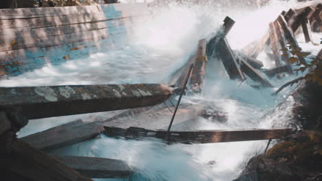 rushing water rapids flowing down log chute and crashing into damaged wooden beams during autumn 4k prores