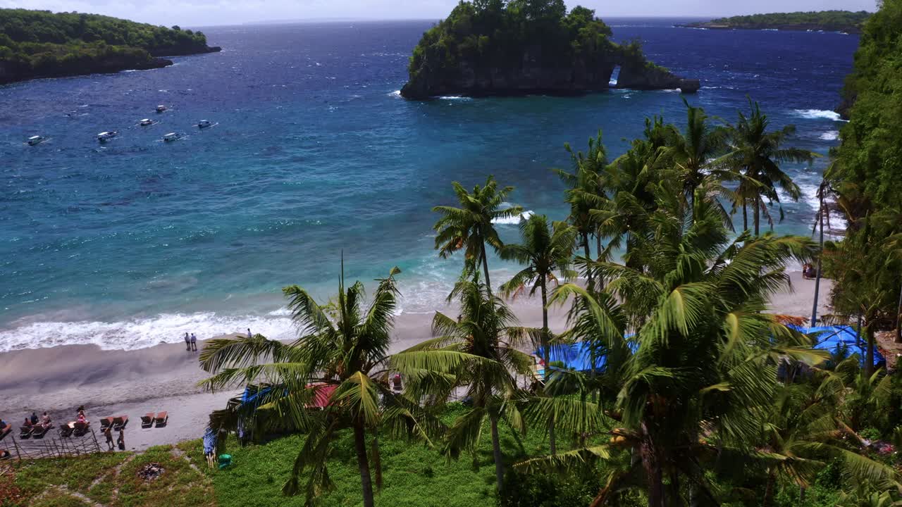 hermosa costa de agua turquesa visible a través de la cima de las palmeras - playa de crystal bay, nusa penida - cerca de bali, indonesia